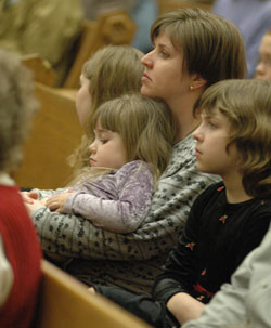 Regina Gerstbauer sits on the lap of her mother, Cindy, during the Feb. 26 Mass in honor of St. Theodora Guérin at St. Louis Church in Batesville. Regina’s sister, Rachel, sits to the right of their mother. All are members of St. Louis Parish.