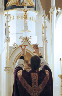 Father Jonathan Meyer, the pastor of St. Anne and St. Joseph parishes in Jennings County and St. Mary Parish in North Vernon, elevates the Body and Blood of Christ during a March 29, 2009, Mass at St. Anne Church. Thieves broke into St. Anne Church during the night on Dec. 27 or the early morning hours of Dec. 28 and took a 700-pound safe containing antique gold sacred vessels. (File photo by Mary Ann Wyand)