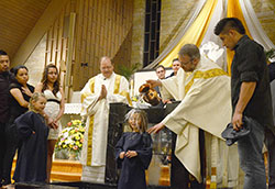 Bailey Wilson is baptized by Father Eric Johnson, pastor at Our Lady of Perpetual Help Parish in New Albany, during the Easter Vigil at the parish’s church on April 19. Deacon Jeffrey Powell assists Father Johnson. (Submitted photo by Crit Fisher)