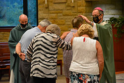 Archbishop Charles C. Thompson ritually lays his hands upon Mark John during the archdiocese’s annual Substance Addiction Ministry (SAM) Mass, held this year at St. Bartholomew Church in Columbus on Aug. 12. Father Christopher Wadelton, pastor of St. Bartholomew, looks on as Denny, left, and Debbie Frey and Mark’s wife Sue join in the blessing. The Johns are members of St. Ambrose Parish in Seymour. Their friends, the Freys, are members of St. Joseph Parish in Shelbyville. (Photo by Natalie Hoefer)