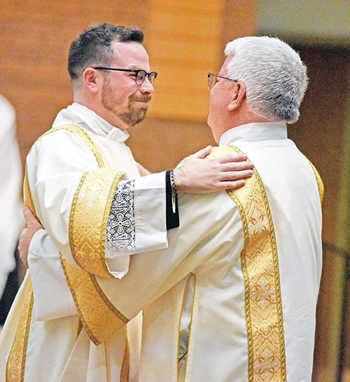 Newly ordained transitional Deacon Liam Hosty beams with joy while exchanging a sign of peace with his father, Deacon Tom Hosty, an archdiocesan permanent deacon, on April 27 during the Mass at St. Barnabas Church in Indianapolis in which Deacon Liam was ordained. Deacon Liam and Deacon Tom are the first father and son to be deacons in the history of the archdiocese. (Photo by Sean Gallagher)