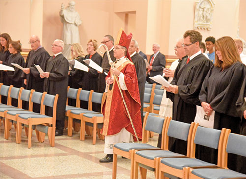 Archbishop Charles C. Thompson processes into SS. Peter and Paul Cathedral in Indianapolis on Oct. 1 at the start of the annual Red Mass of the St. Thomas More Society of Central Indiana. Standing at the front of the congregation are judges wearing their black judicial robes. (Photo by Sean Gallagher)